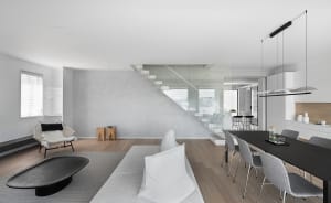 Modern minimalist living space featuring a concrete staircase, glass railings, and a contemporary furniture design.