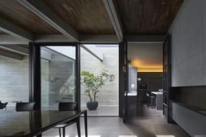 Modern residential kitchen featuring concrete walls, glass windows, and metal fixtures.