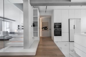 A modern residential kitchen with white tile flooring, wooden cabinets, and a minimalist design.