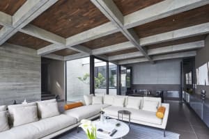 Modern industrial living room with concrete ceiling, white furniture, and open space.