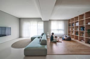 A modern minimalist living room with neutral-colored furniture and a large bookshelf.