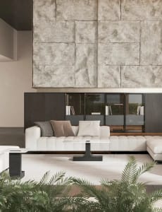 A modern living room with a white sectional sofa, concrete accent wall, and green plants.