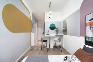 A minimalist bedroom featuring geometric wall art and a low-profile bed with a single decorative pillow.