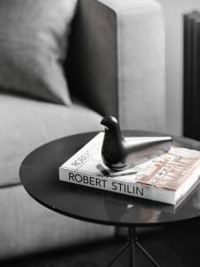A modern black metal bird decorative figurine placed on top of a coffee table in a living room setting.