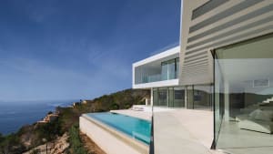 Modern house featuring glass, concrete, and steel exterior with sea view.