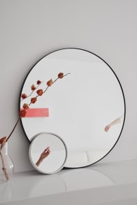 A minimalist interior design with a large circular mirror made of glass.