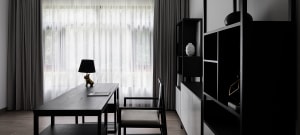 A modern home office with a black desk, white curtains, and a minimalist design.