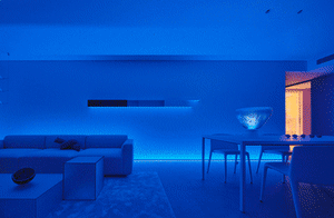 A minimalist modern living room with blue furniture and black accent pieces.