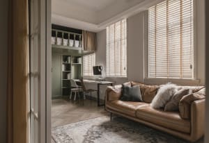 Modern living room office with wooden furniture, leather couch, and blinds on windows.