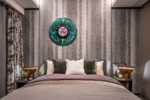 A modern industrial bedroom featuring a large bed with metal headboard, mixed textiles, and metallic decorative elements.