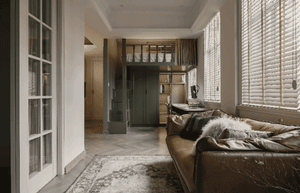 A modern living room featuring a brown leather sofa adorned with patterned pillows and a patterned rug.