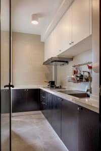 Modern minimalist kitchen with black cabinets, white countertops, and concrete flooring.
