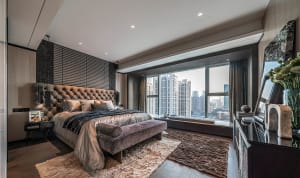 Modern bedroom with fabric headboard, glass windows, metal accents, and wooden flooring.