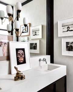 Modern bathroom with concrete countertop and wall-mounted sink, framed photographs on textured wall, and brass pendant light 