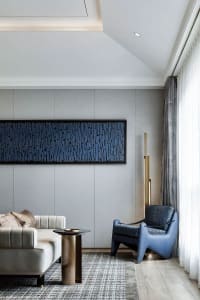 A modern living room featuring a fabric wall art piece and a combination of furniture with a blue accent chair and a white so