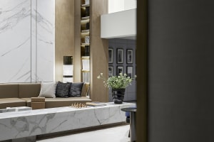 An elegant modern living room with marble elements and a sofa adorned with cushions and a chessboard.