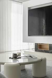 A modern living room features white terrazzo tables surrounded by upholstered furniture against a minimalist backdrop with ve