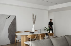 A minimalist living room featuring wooden furniture and a vase with dried grasses on a table.