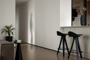 Modern kitchen with concrete countertops and wooden stools.