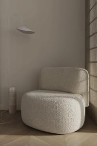 A modern interior with a textured fabric chair and minimalist lamp.