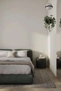 A minimalist bedroom with neutral colors and a black hanging plant.