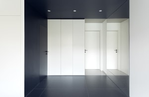 A minimalist white hallway with black accent walls and black-tiled floor.