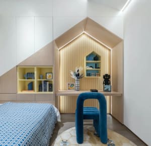 Modern, minimalist bedroom featuring blue accents, a blue upholstered chair, and a blue patterned bedspread.