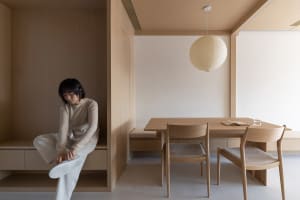 A minimalist dining area featuring wooden furniture and a hanging paper lantern.