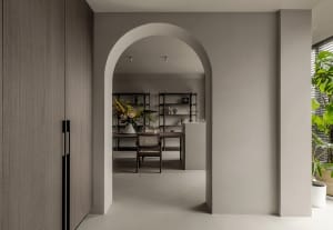 Minimalist living room with concrete walls and floor, featuring natural elements and a single decorative object.