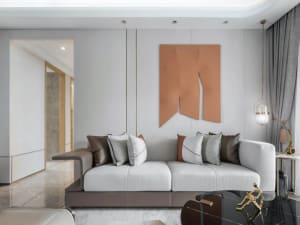 Modern living room with a gray sofa, taupe abstract art, and metallic accents.
