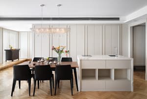 A modern minimalist residential kitchen featuring marble countertops and a central island with an eat-in area.