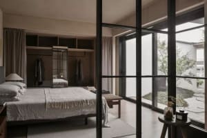 A minimalist bedroom with a wooden bed, white sheets, and a simple wooden side table.