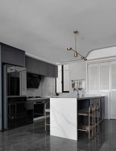 A modern minimalist residential kitchen with a white marble island and black cabinetry.