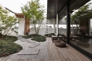 Modern-style Japanese garden with wooden deck, rock pathway, and greenery.