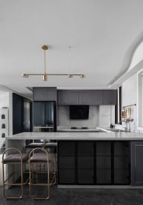 A modern kitchen featuring marble countertops and decorative lighting fixtures.