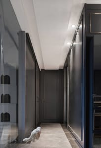 A modern interior corridor with metallic wall panels and a white cat walking on the floor.