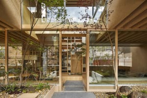 A minimalist residential courtyard featuring glass walls, wooden flooring, and concrete elements.