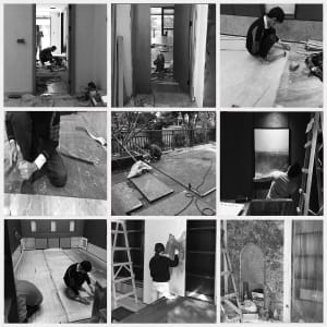 Construction workers installing floor tiles in a residential interior space.