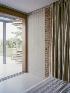 Minimalist bedroom featuring white curtains, wood paneling, and concrete elements.