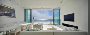 A modern living room featuring clear glass doors that open to reveal an ocean view.