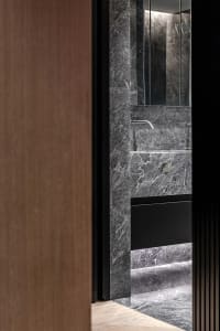 Modern minimalist bathroom with marble walls and black accents.