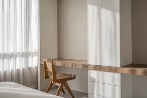 Minimalist bedroom featuring a wooden desk and white curtains