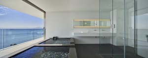 A modern bathroom with glass walls overlooking the ocean