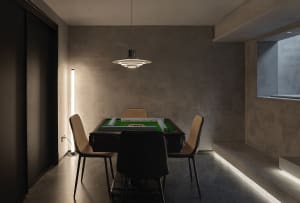 A modern, industrial-style game room featuring a concrete wall and floor, with a mahjong table and chairs.
