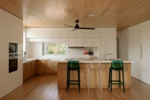 A modern minimalist kitchen with wooden cabinets, white countertops, and a central island.