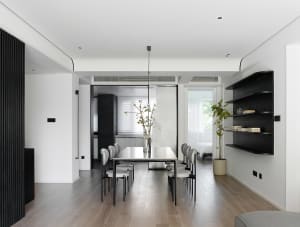 Modern minimalist living room with a wooden floor, white walls, and simple furniture arrangement.
