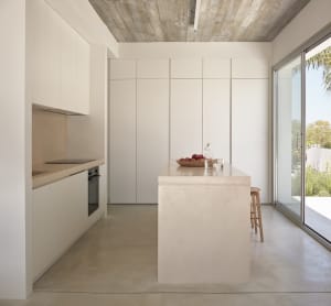 Modern minimalist kitchen with concrete island and white cabinets.