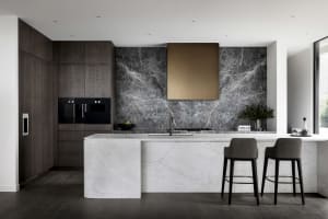 Contemporary residential kitchen featuring dark wood cabinets, a marble backsplash, and a marble kitchen island.