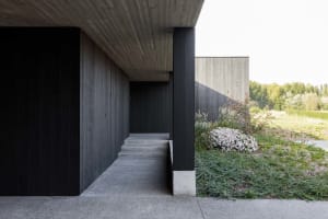 Modern residential exterior featuring concrete walls and wooden columns.