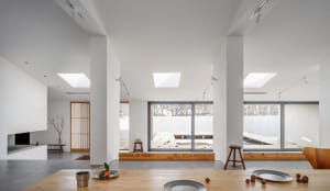 Modern minimalist living room featuring concrete floors, wooden furnishings, and large glass windows.